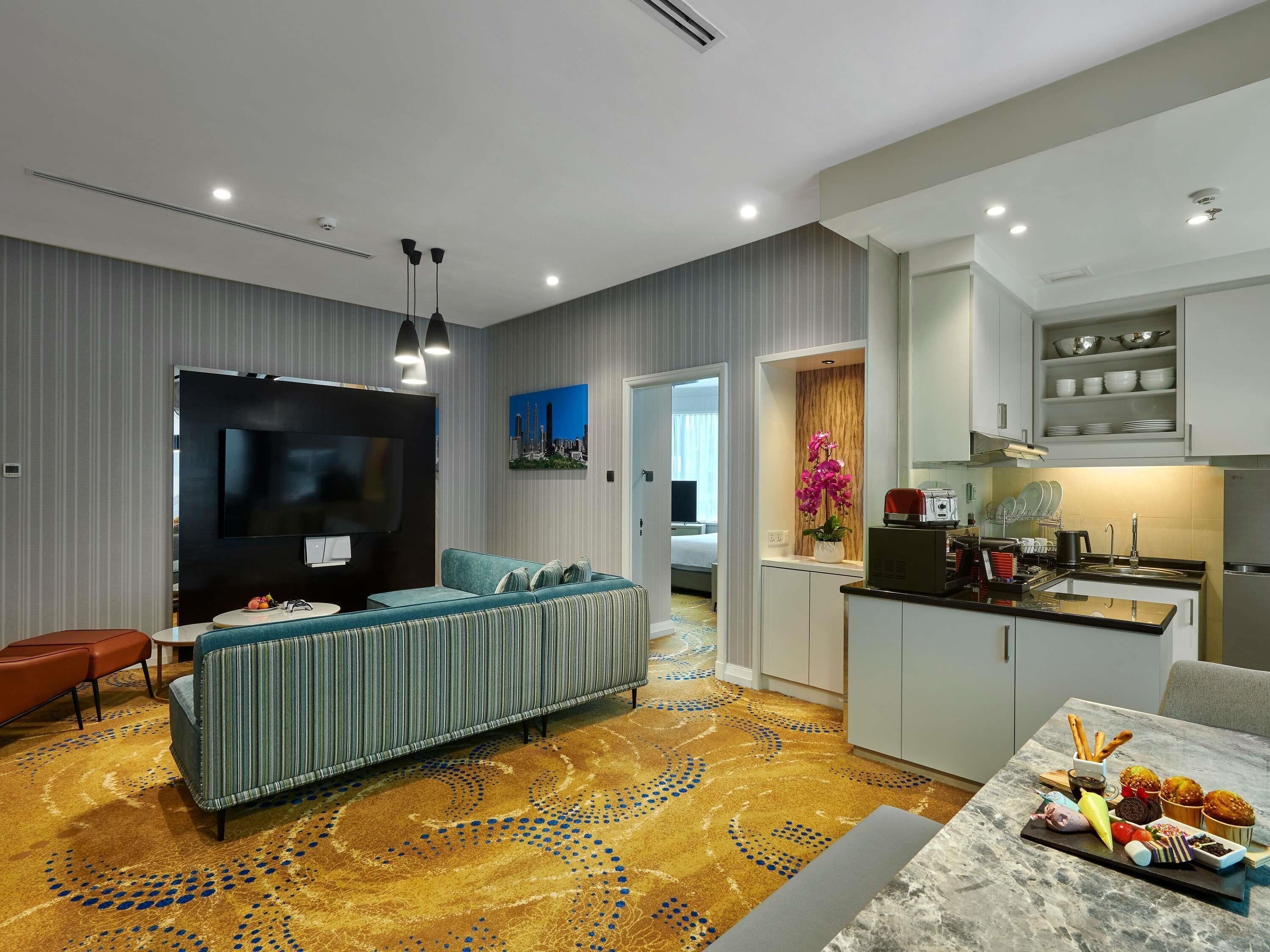 A modern living room with a sofa, TV, and a dining area with a marble table and food.