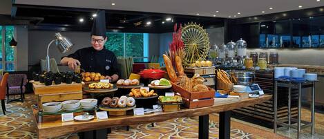 A buffet with various food items and a chef serving.