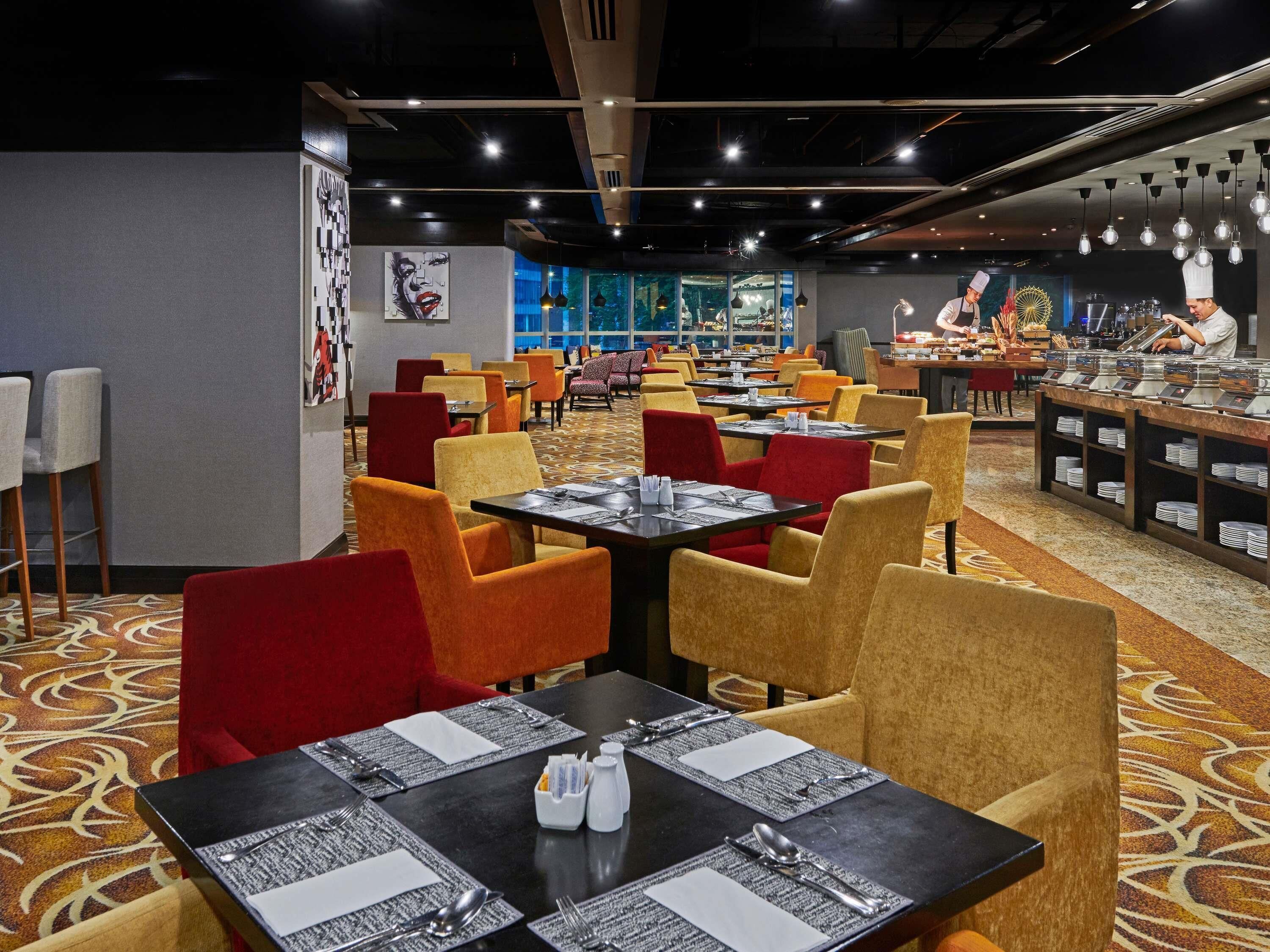 Un restaurante con varias mesas y sillas, una zona de bufé y un chef preparando comida.