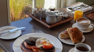 Una mesa de desayuno con platos de comida, una taza de café y una bandeja con salsas.