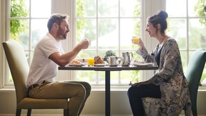A dining table with breakfast items, two people seated, and a window with greenery outside. - Rufflets St Andrews (St. Andrews)