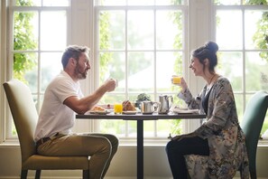 Enjoy a peaceful breakfast for two in this serene room with a view of lush greenery.