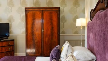 Un dormitorio con cama, armario, lámpara y televisor sobre una cómoda.