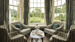A room with two armchairs, a table with tea service, and a view of a garden through large windows. - Rufflets St Andrews (St. Andrews)
