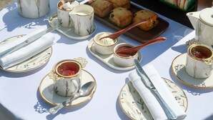 A table set for a tea service with a variety of pastries and sandwiches.