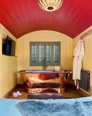 Bathroom features a copper bathtub, wooden ceiling, and large window with shutters.