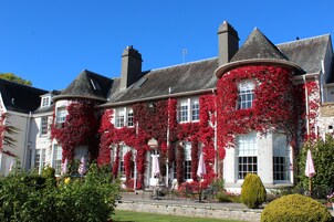 Un edificio con paredes cubiertas de hiedra roja, numerosas ventanas y zonas de estar al aire libre.