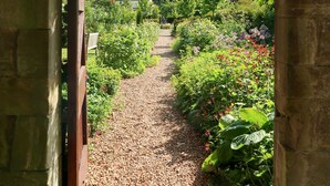 An arched stone pathway leading through a garden with various plants and flowers. - Rufflets St Andrews (St. Andrews)