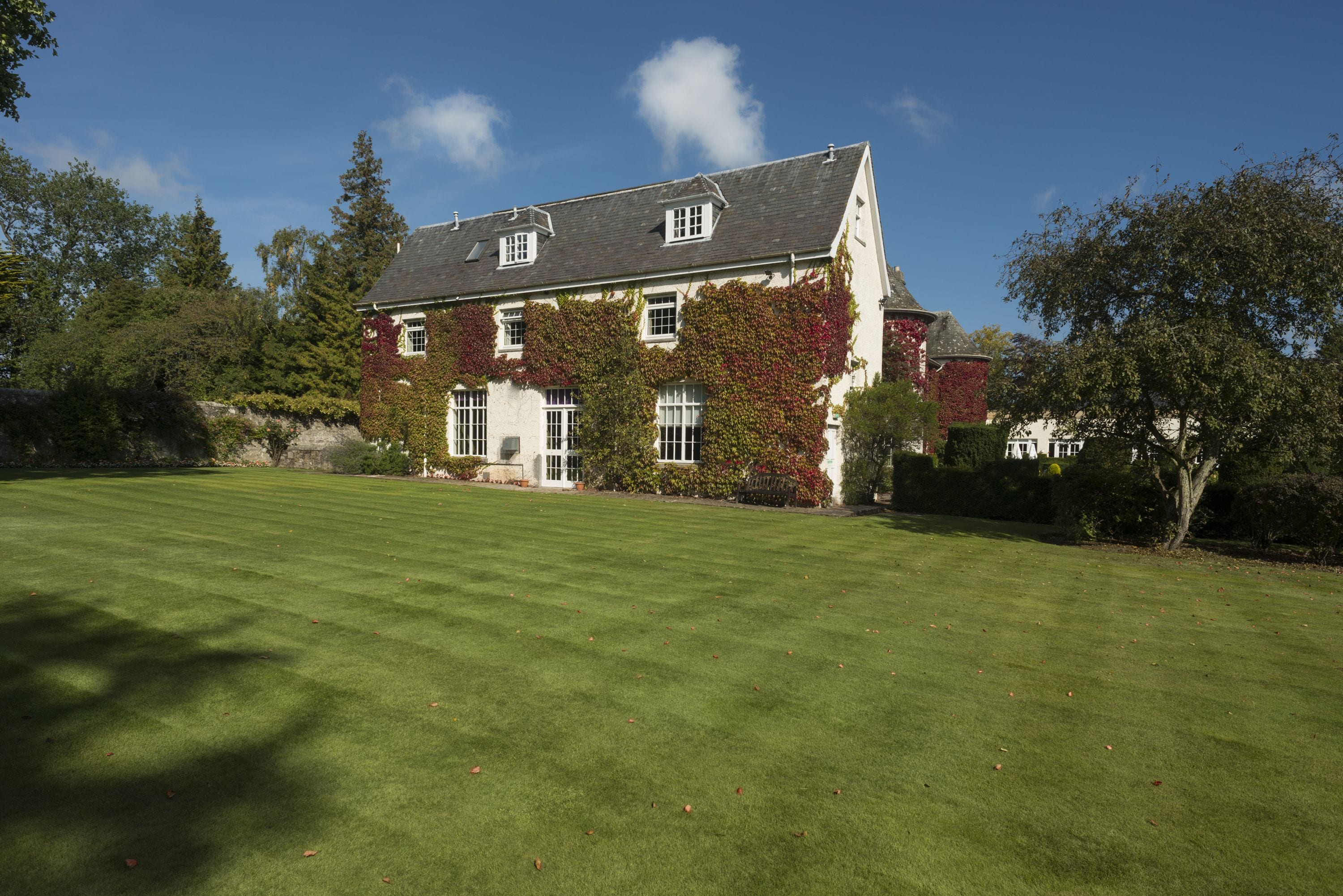 A large, two-story house with a well-maintained lawn in front.