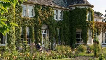 A large, ivy-covered building with a well-maintained garden in front.