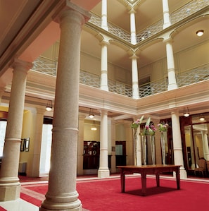 A grand lobby with high ceilings, large columns, and a red carpet.