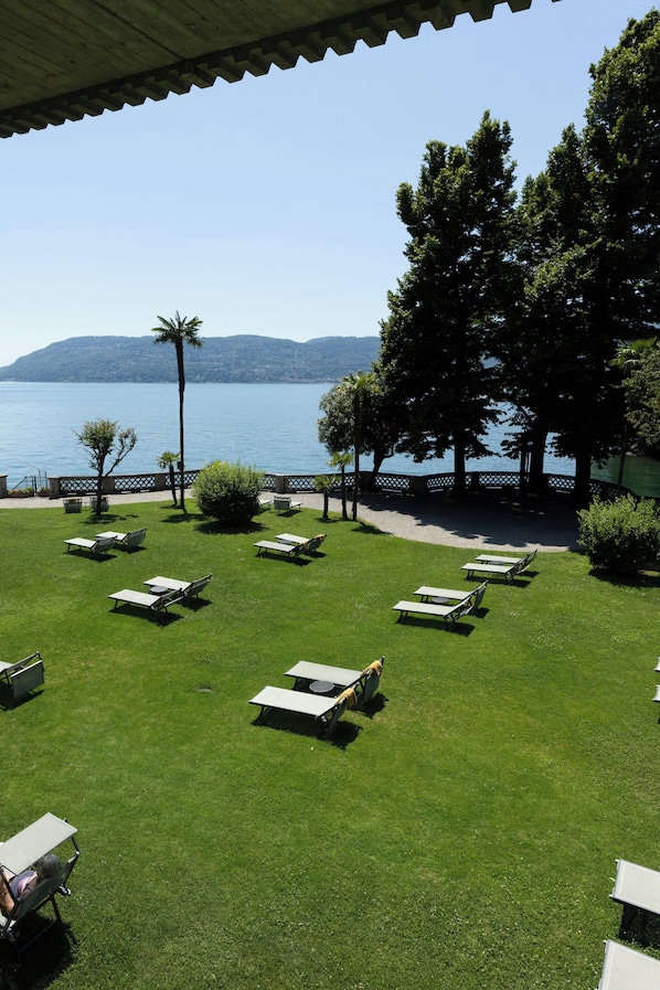 Un espacio al aire libre con césped, mesas de picnic y vista a un lago.
