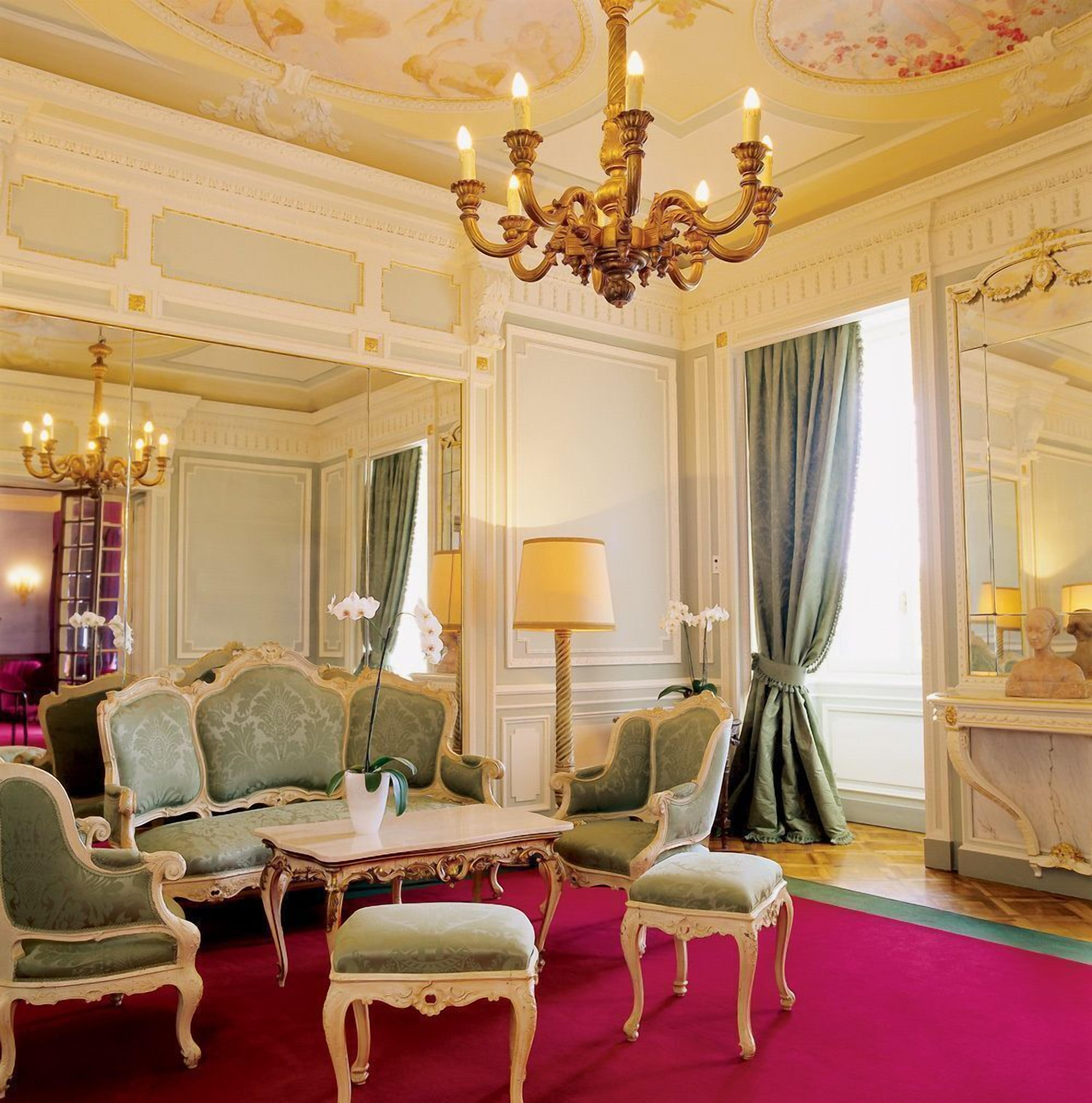 Una habitación lujosa con muebles ornamentales, un candelabro y un espejo grande.