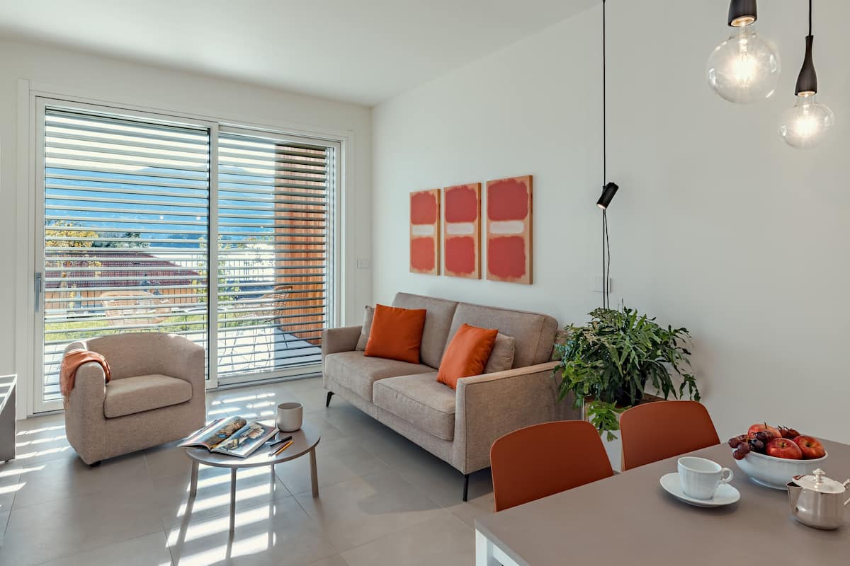 Een moderne woonkamer met een bank, salontafel en een eethoek met een gedekte tafel voor thee.