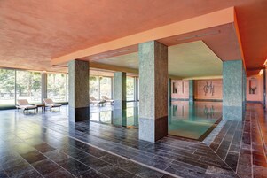 Una piscina techada, sillones reclinables de piscina