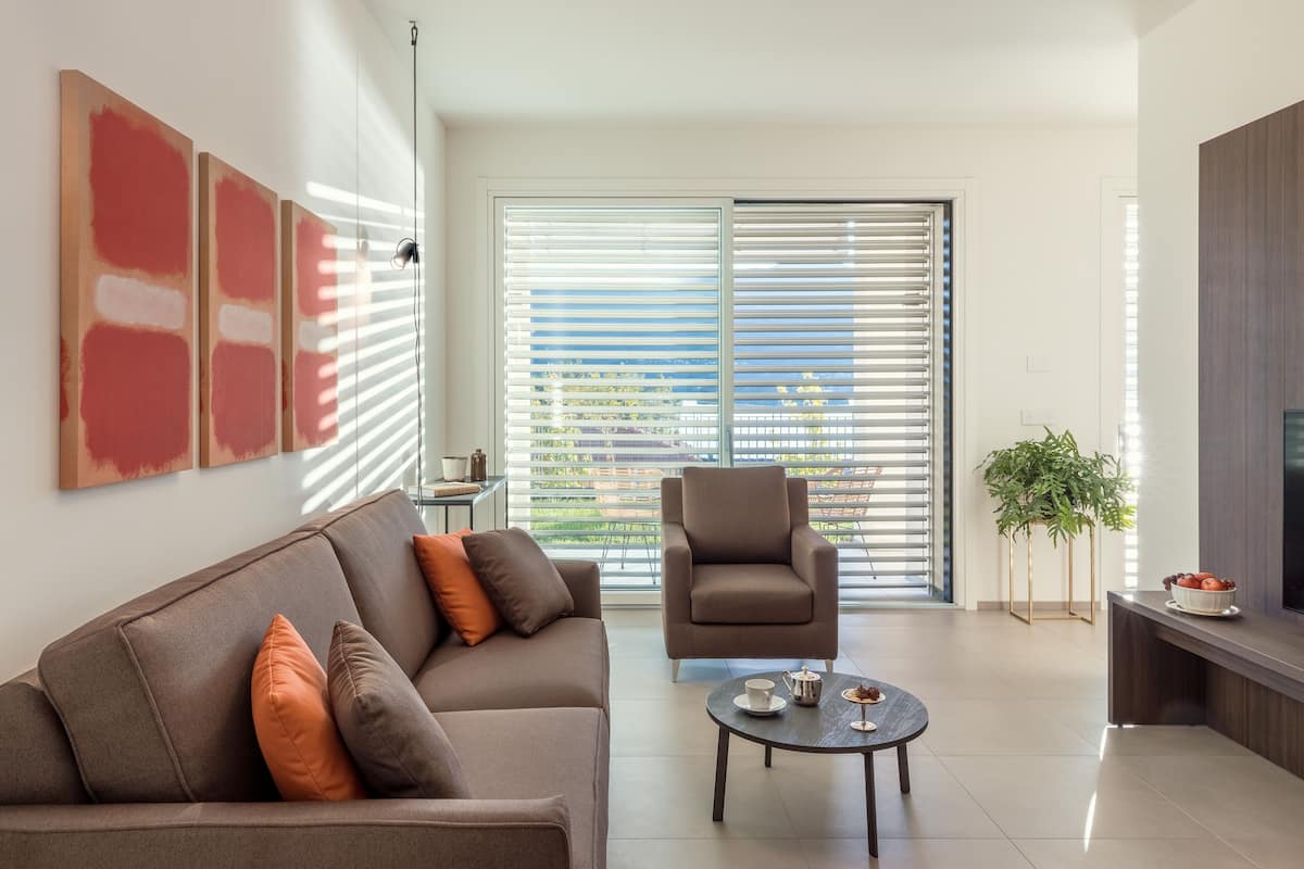 Een moderne woonkamer met een bank, fauteuil, salontafel en een tv op een dressoir.