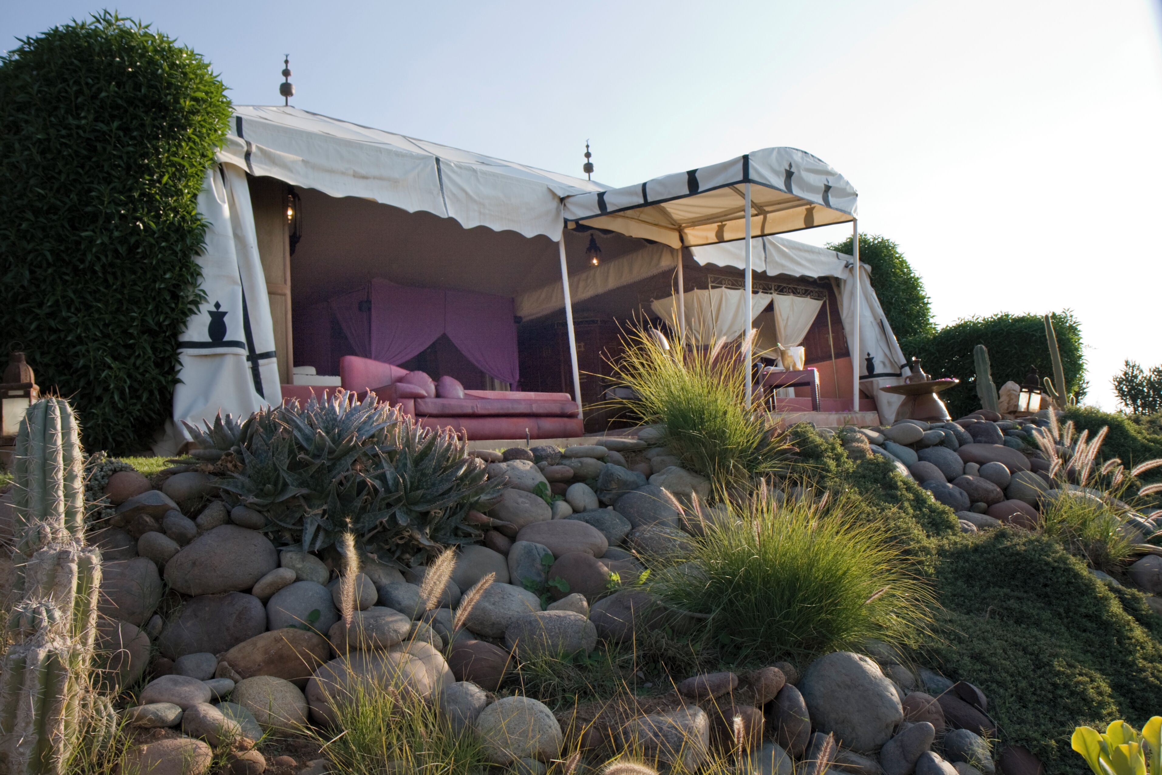 A tented outdoor area with a seating arrangement and a rock garden.