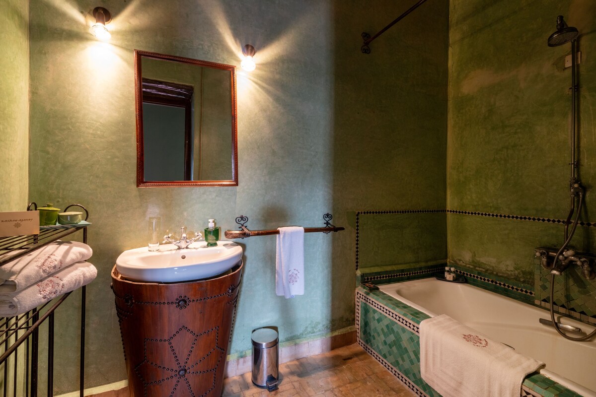 A bathroom with a wooden tub, a sink, a mirror, and a shower.