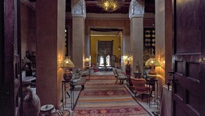 A corridor with ornate columns, patterned rugs, and traditional lamps. - Kasbah Agafay Hotel And Spa (Tameslouht)