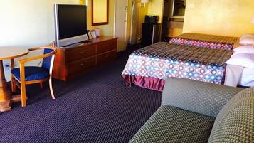 Una habitación de hotel con cama, escritorio, silla, televisor, cómoda y espejo.