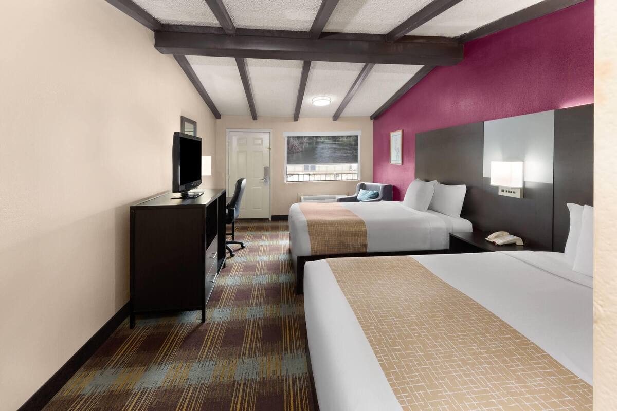 Une chambre d’hôtel comprenant un lit, un bureau, une télévision, une fenêtre avec vue et une tête de lit dotée d’une lampe.