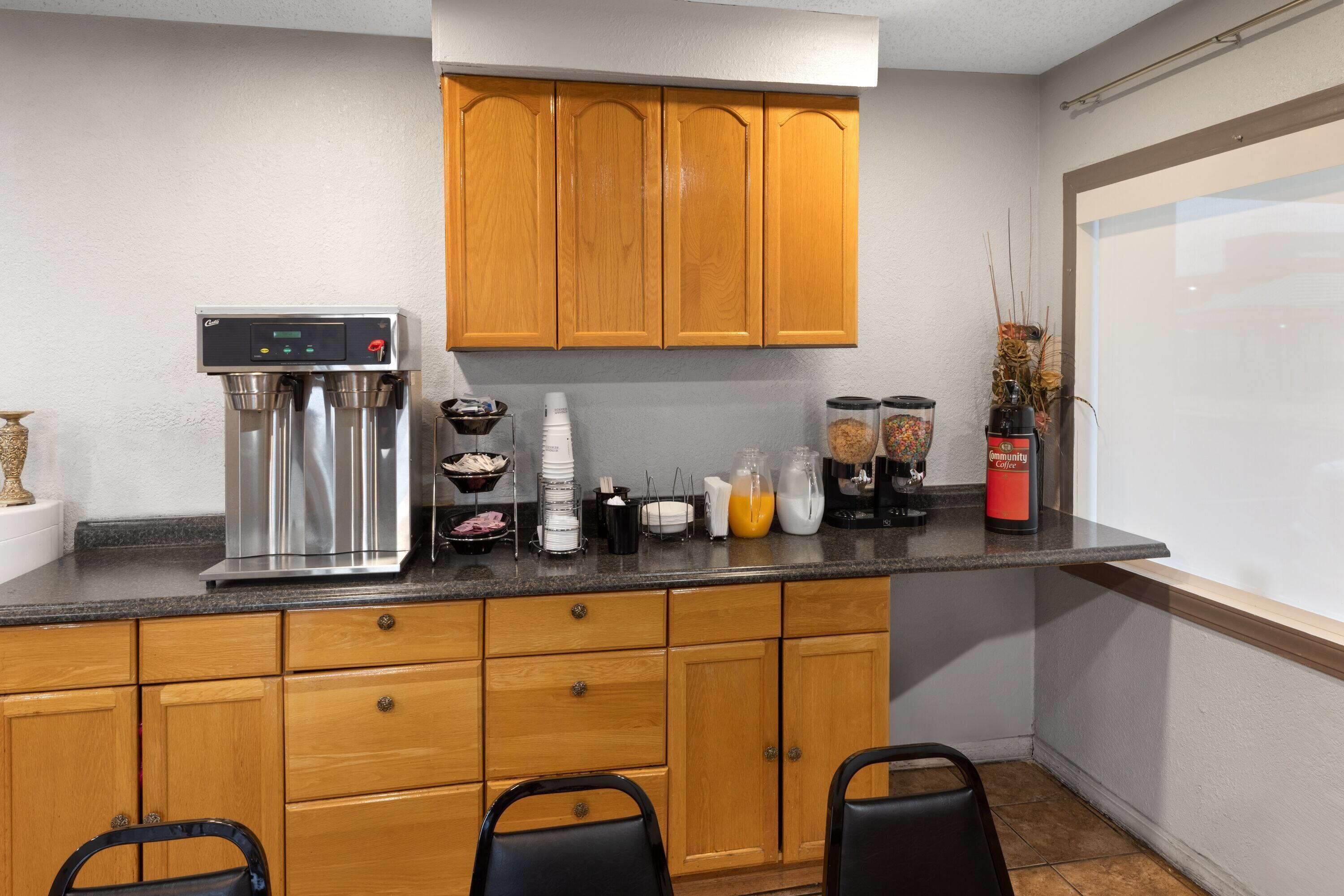 Una cocina compacta con armarios de madera, una cafetera de acero inoxidable y un preparador de café.