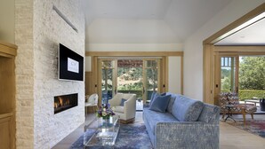 Una sala de estar moderna con chimenea de piedra, un sofá grande y una mesa de centro de vidrio.