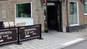 The exterior of Strand Hotel with a prominent entrance, a signboard for the hotel, and Swedish flags displayed on the roof.