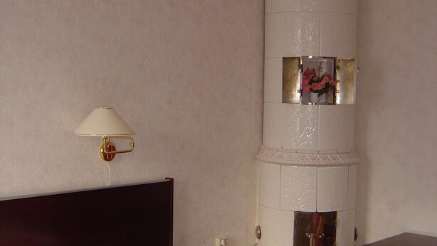 Une chambre d’hôtel comprenant un lit, une table de chevet, une lampe et une colonne décorative.
