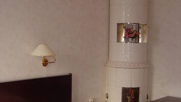 Una habitación de hotel con una cama, una mesita de noche, una lámpara y una columna decorativa.
