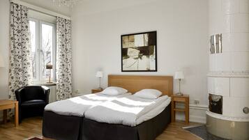 A bedroom with a bed, a chair, a small table, a lamp, and a fireplace.