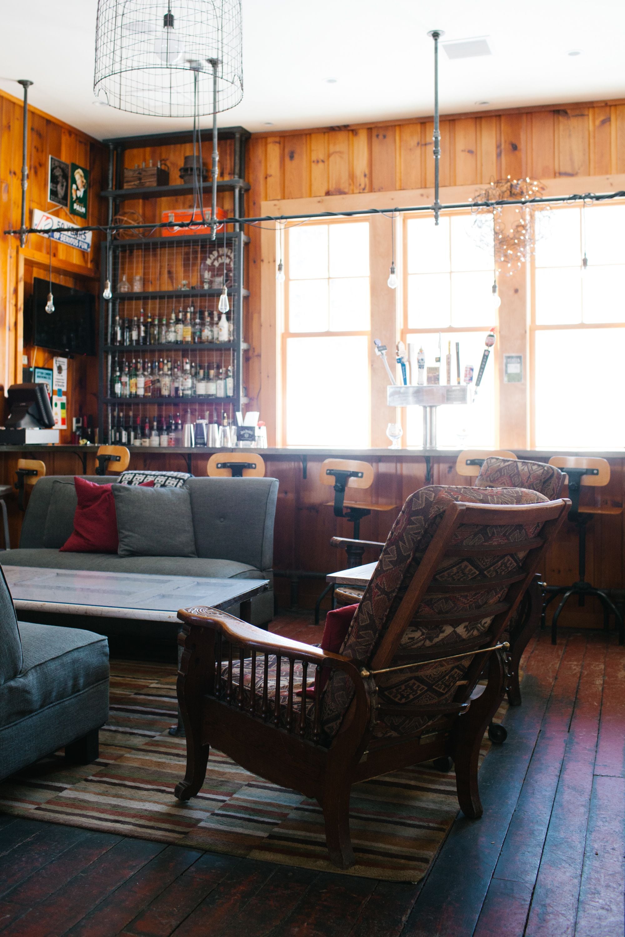 Un rincón de bar acogedor con paredes de madera, una barra y un área de estar con un sofá y sillones estampados.