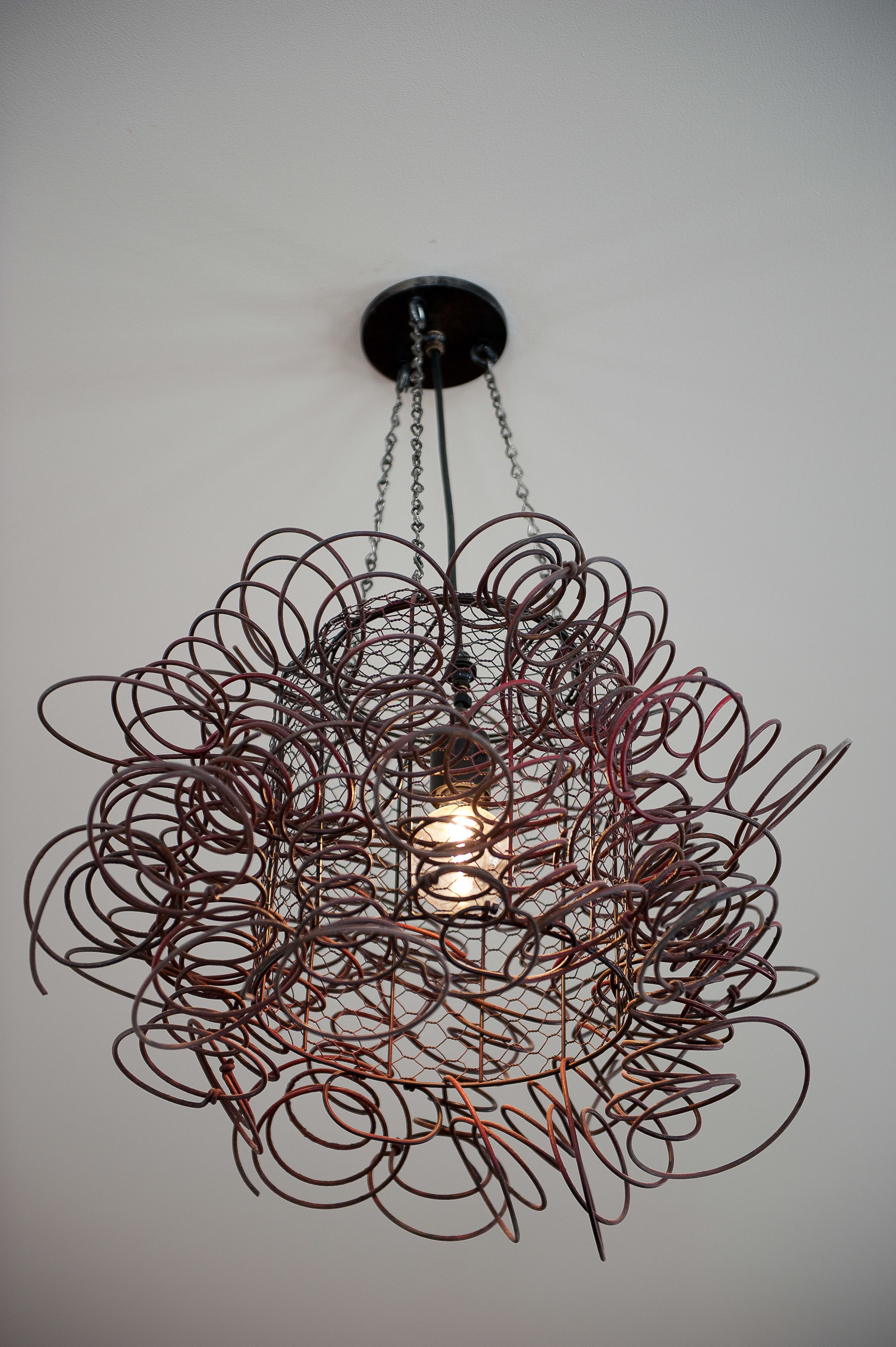 A ceiling light fixture with a complex, intertwined metal design.
