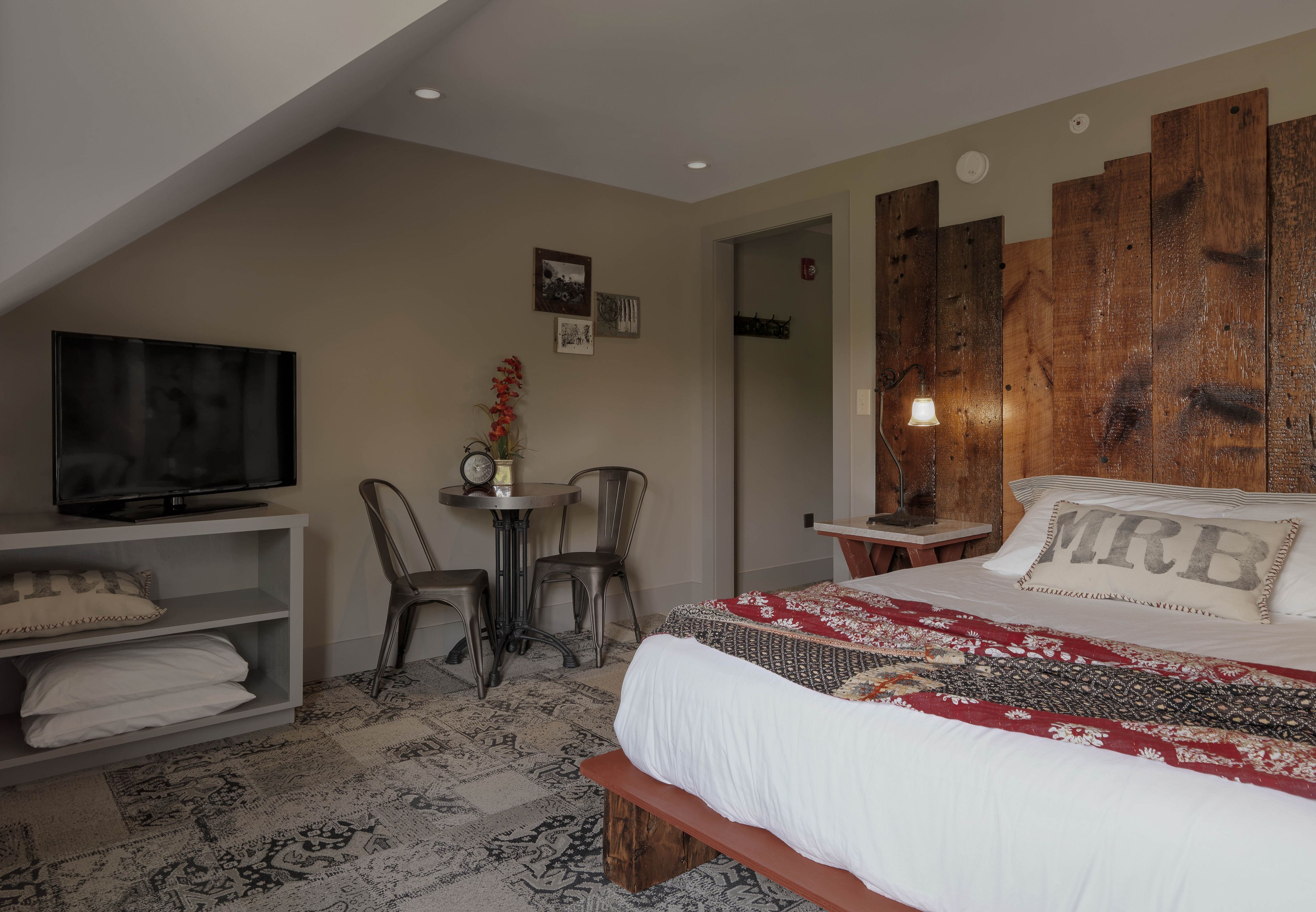Een slaapkamer met een bed, een televisie, een tafeltje en stoelen.
