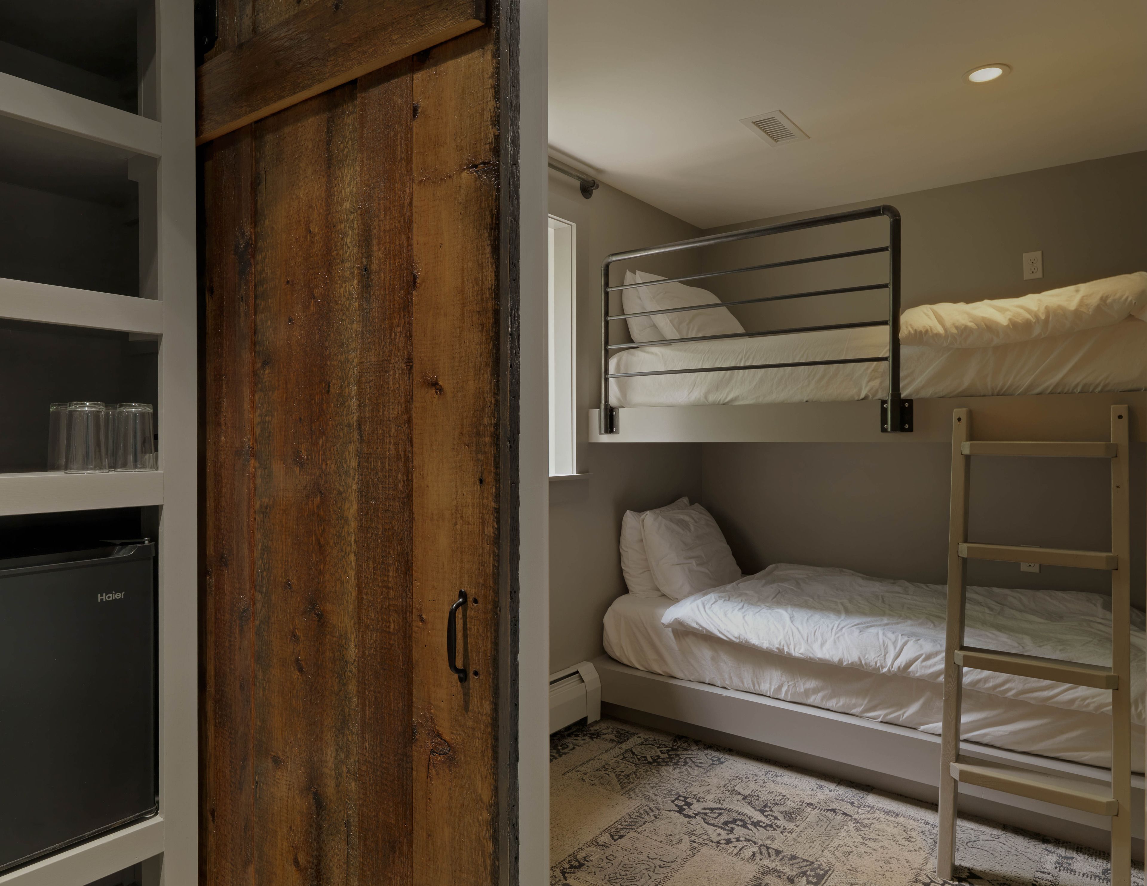 A compact room with a bunk bed, a wooden wardrobe, and a radiator.