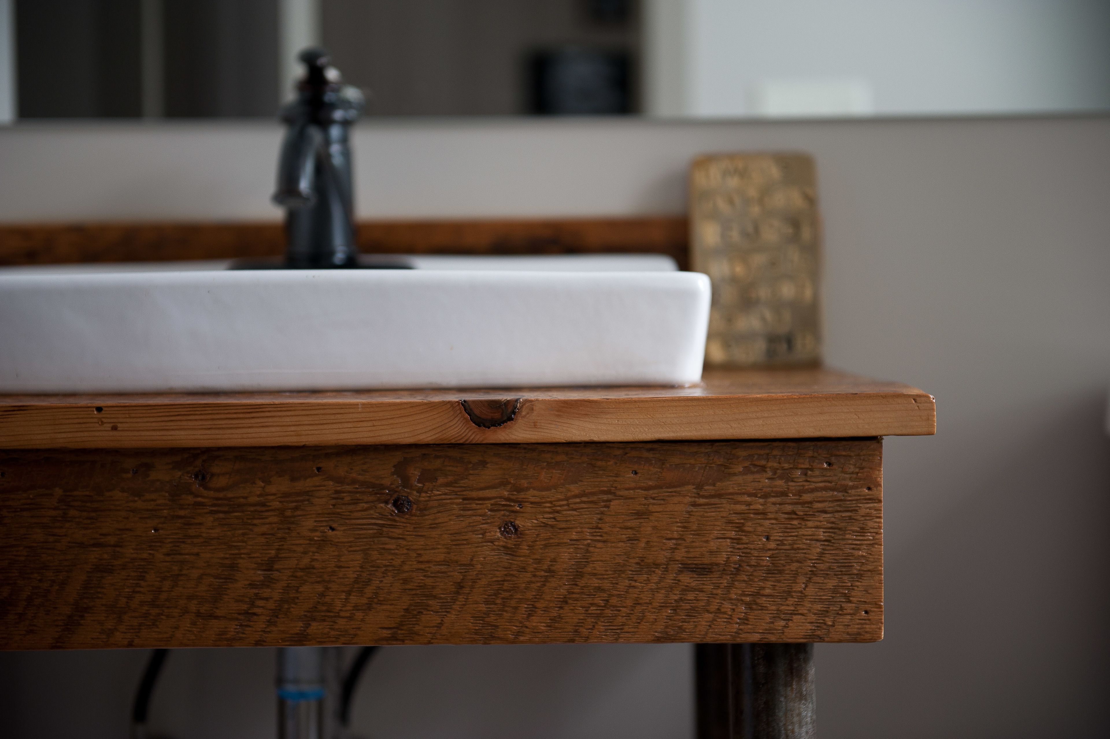 A wooden table with a white sink and a faucet.