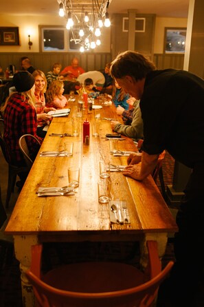 A long wooden table set for a meal with multiple chairs around it. - Mad River Barn (Waitsfield)