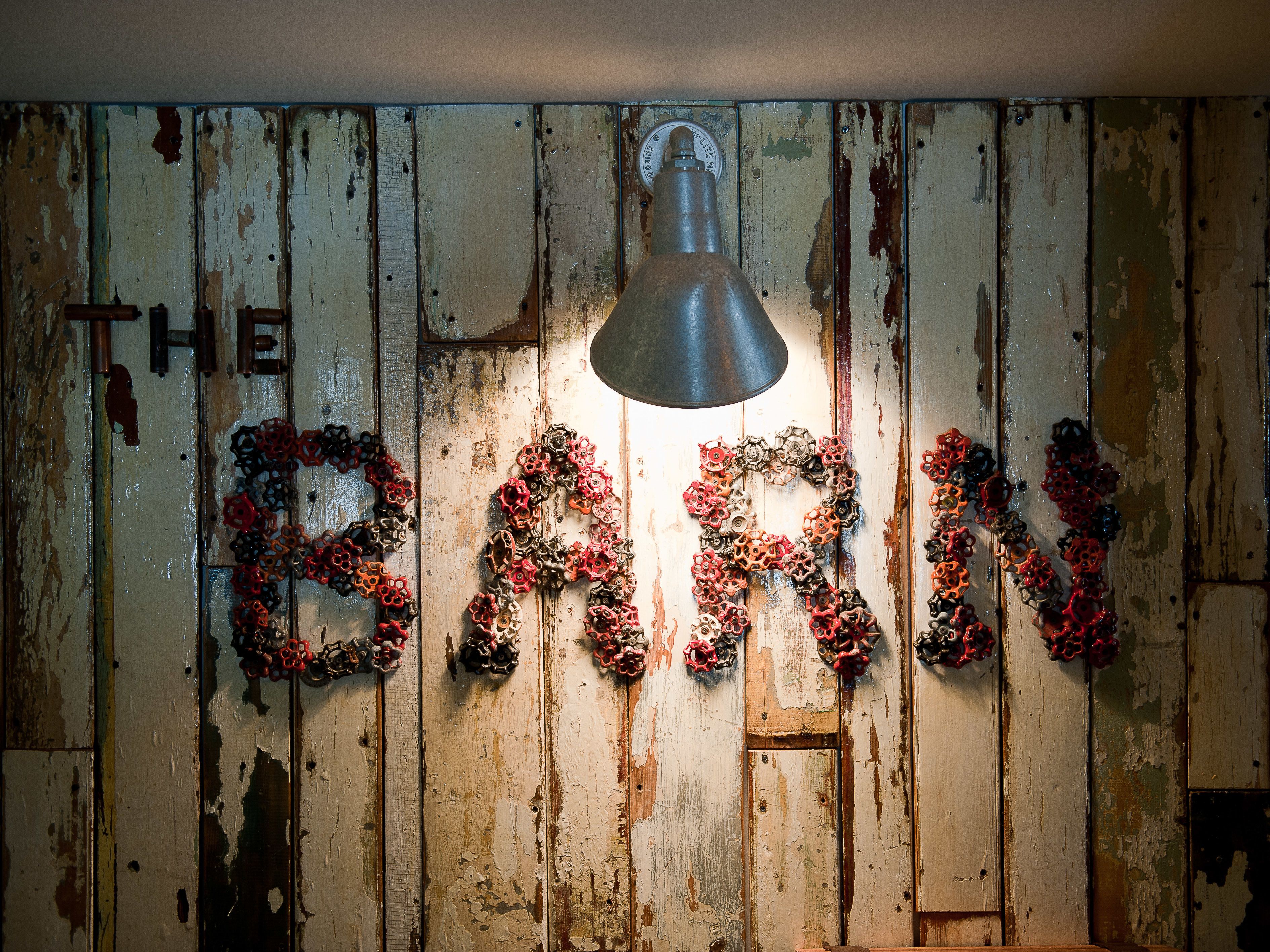 A rustic barn wall with the words "THE BARN" spelled out in decorative metal letters.