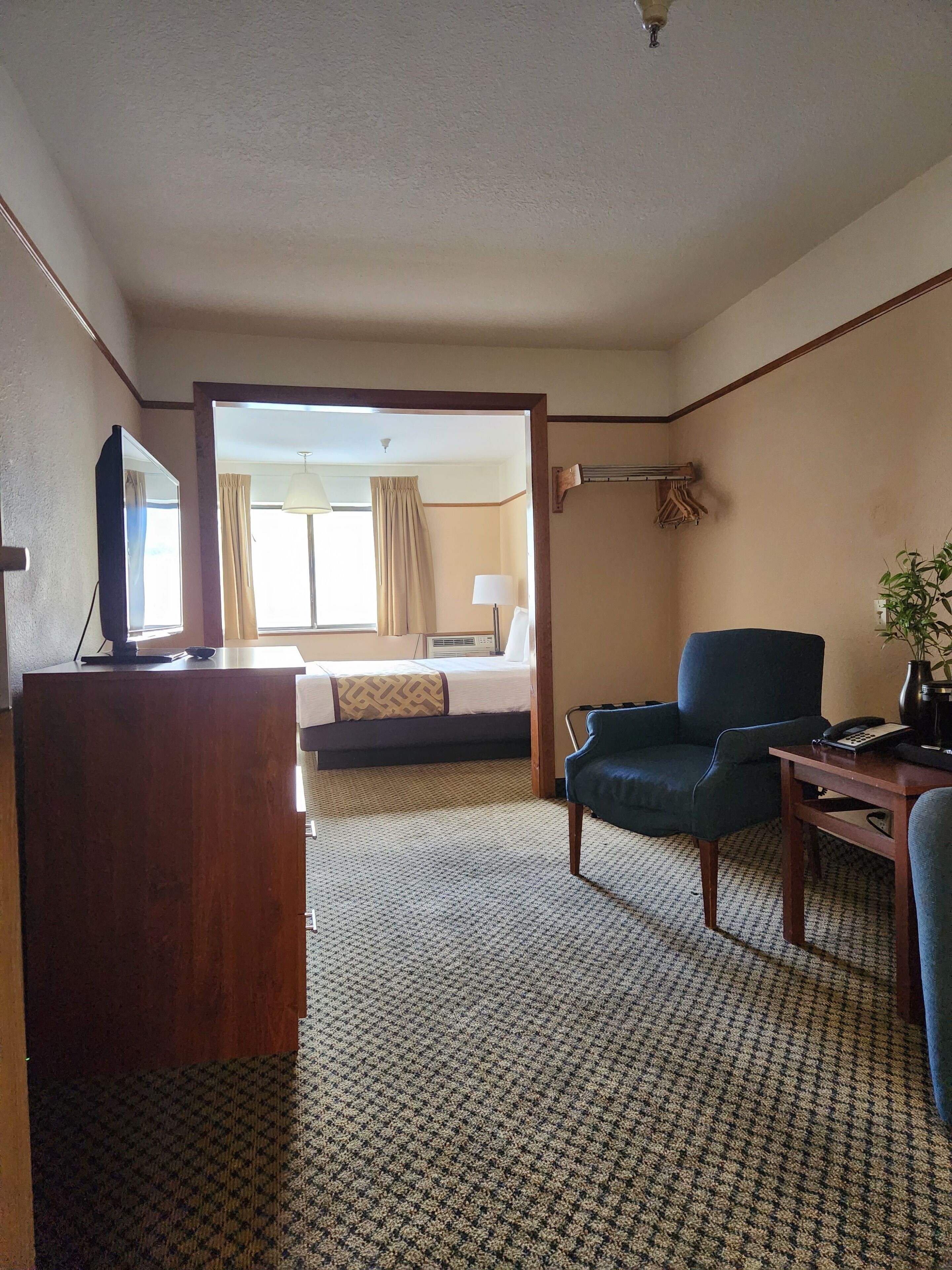 A hotel room with a bed, a desk, a chair, a television, and a window with curtains.