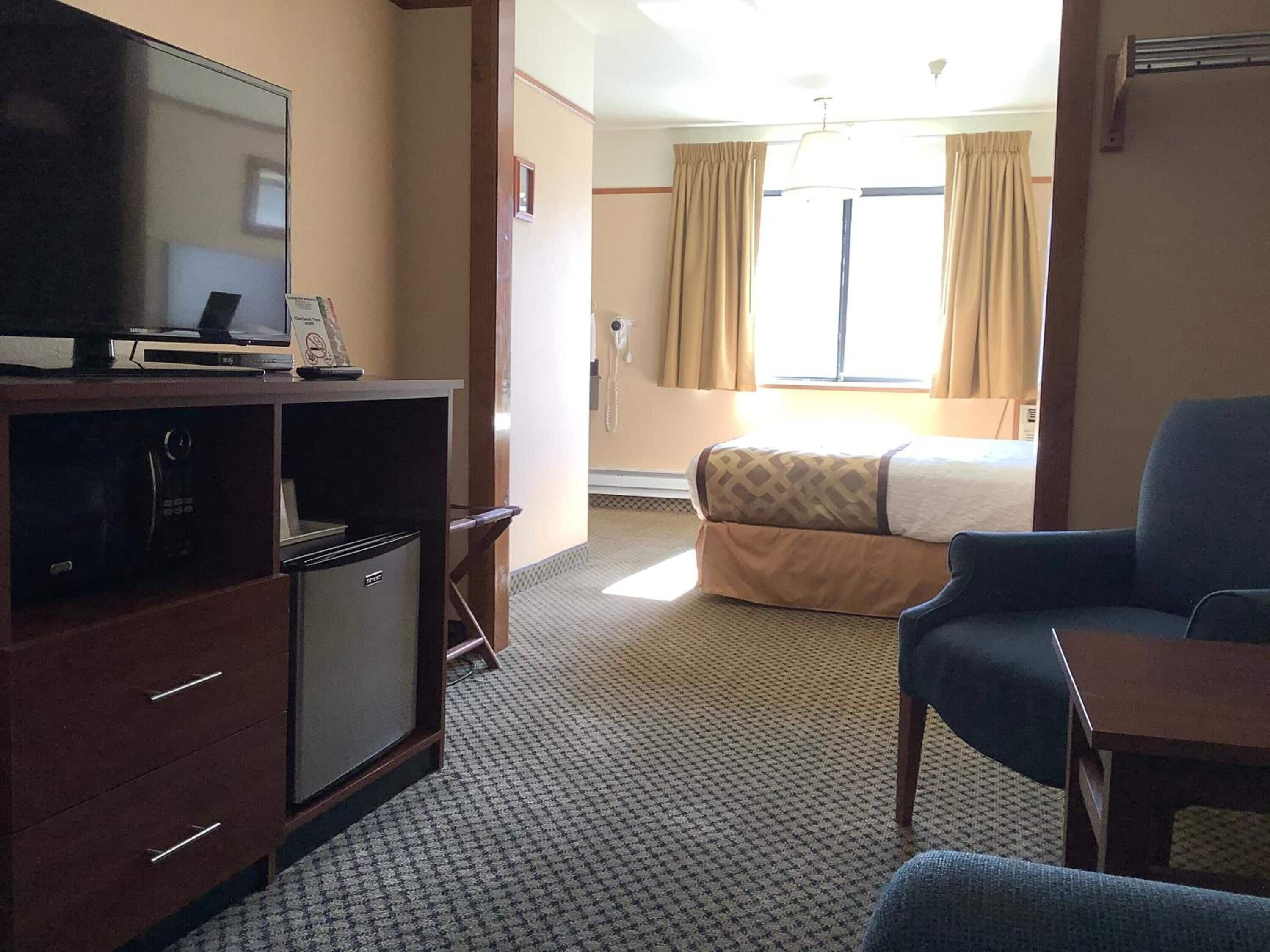 Une chambre d’hôtel équipée d’un lit, d’une télévision, d’un bureau et d’une petite kitchenette.