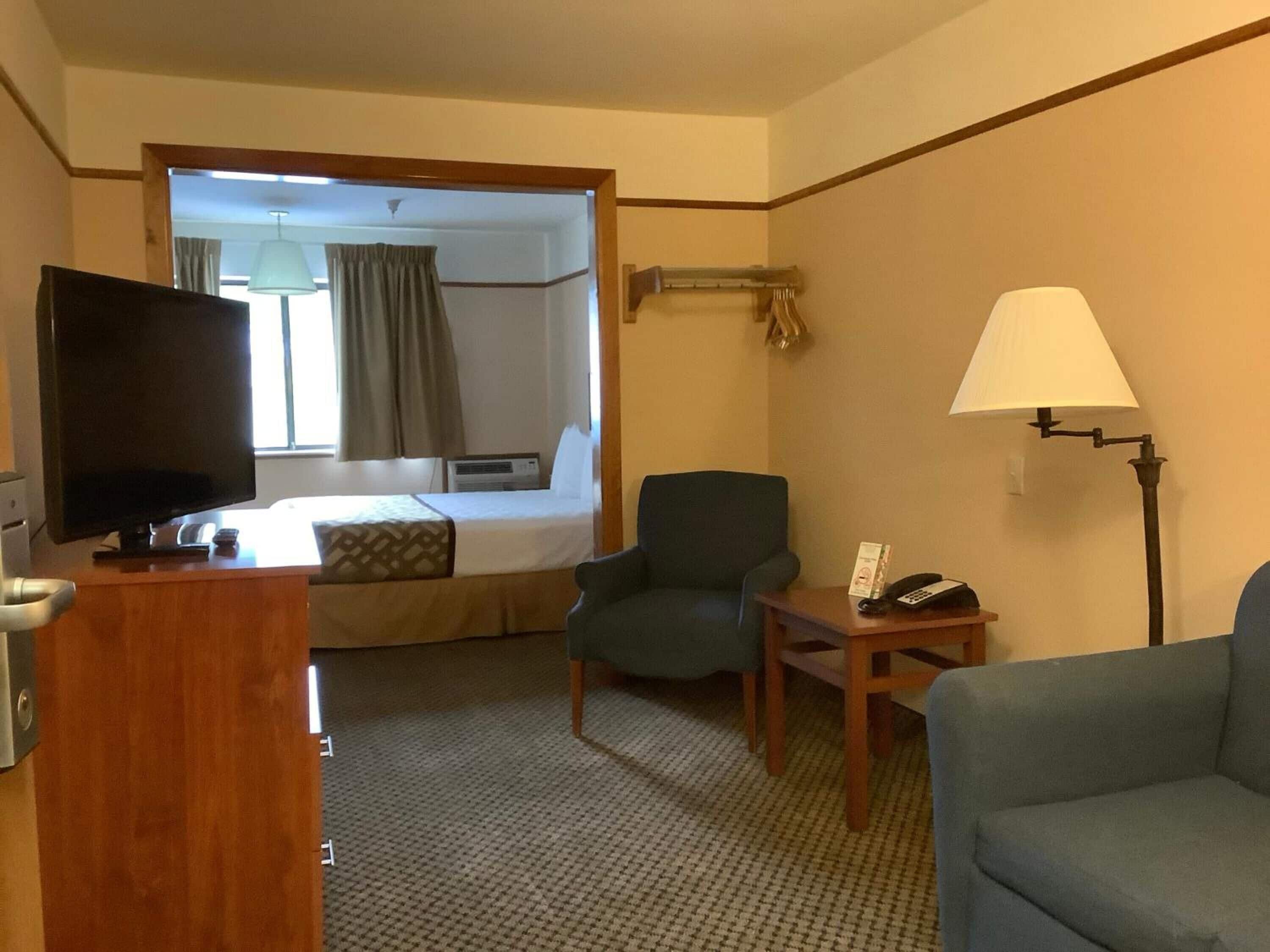 A hotel room with a bed, a television, a desk, a chair, and a lamp.