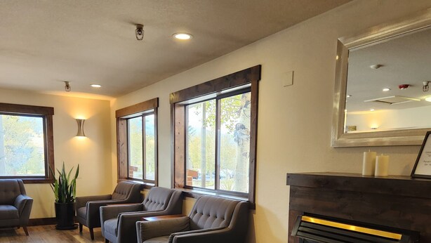 A cozy living room with a fireplace, comfortable seating, and large windows.