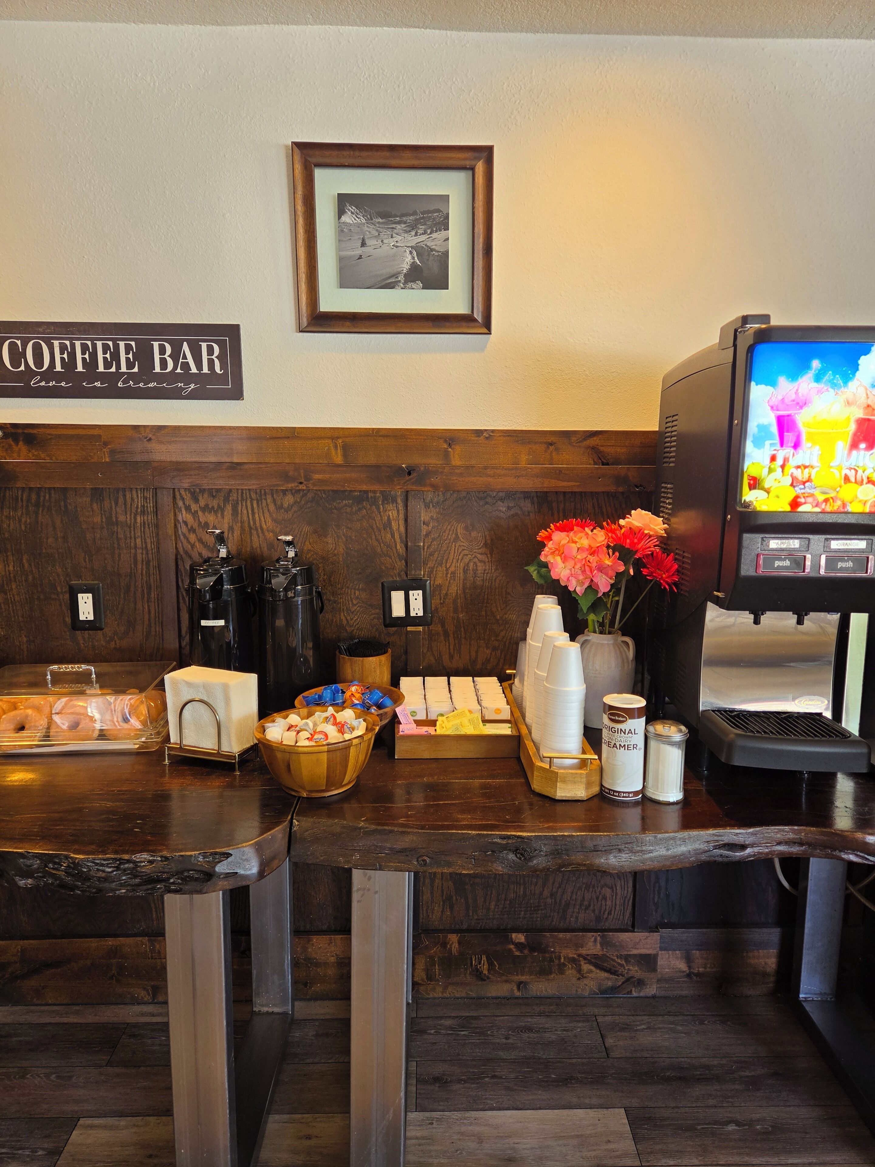 A coffee bar with a sign, a framed picture, and a coffee machine.