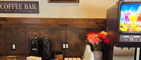 A coffee bar with a sign, a framed picture, and a coffee machine.