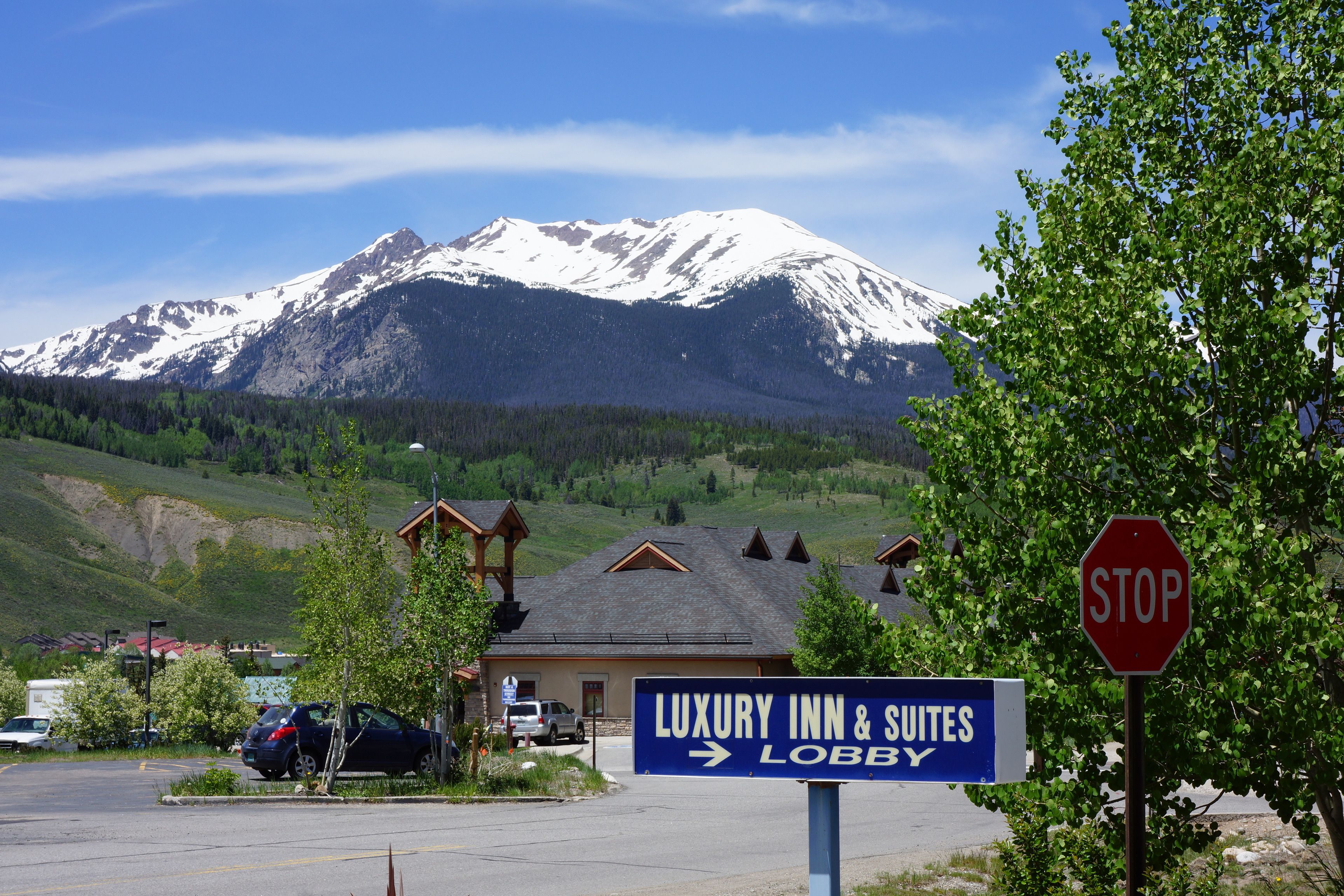 A sign for a luxury inn and suites with a mountain view in the background.