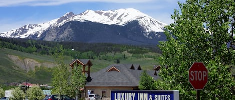 A sign for a luxury inn and suites with a mountain view in the background.