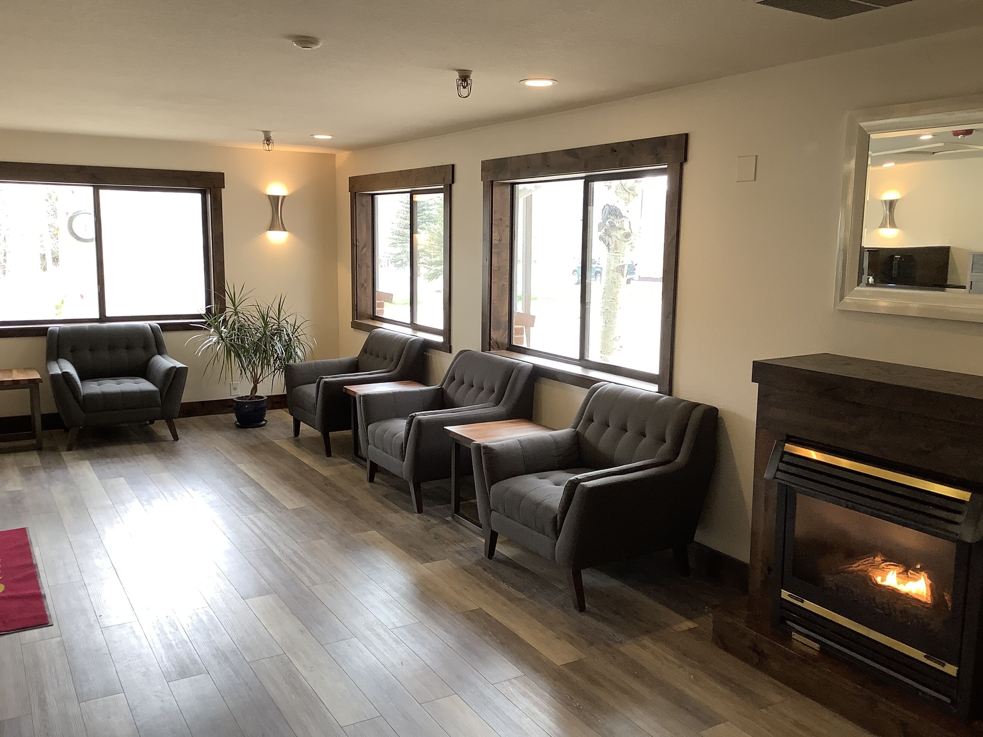 A cozy seating area with leather sofas and armchairs, a fireplace, and large windows allowing natural light.