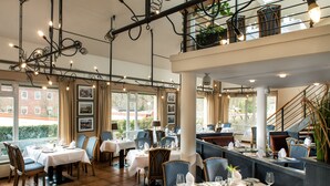Un restaurante con varias mesas, sillas y una escalera que lleva a un nivel superior.