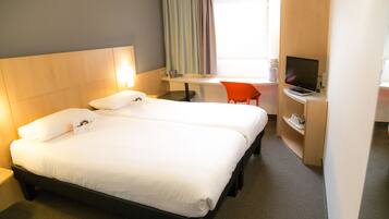 A hotel room with two beds, a desk with a laptop, a chair, and a TV.