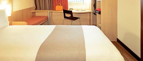 A hotel room with two beds, a desk, a chair, a window with curtains, and a wardrobe.